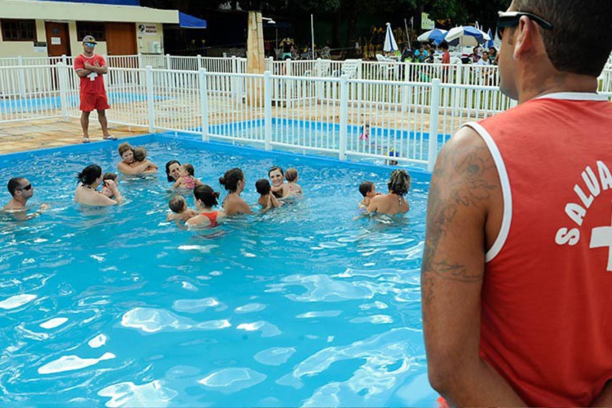 Banhistas olhando pais e crianças banhando em piscina de clube, para evitar afogamento