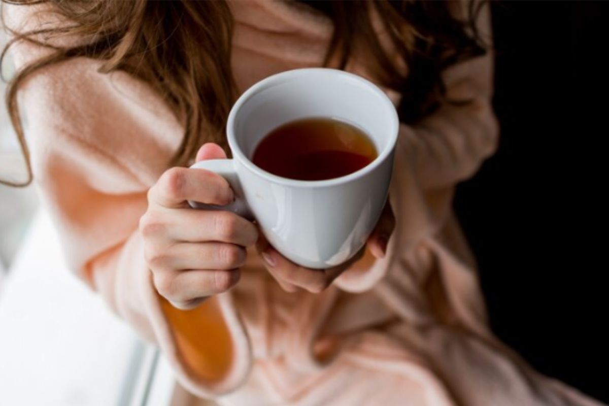 mulher segurando uma xícara de chá de camomila antes de dormir para melhorar o sono