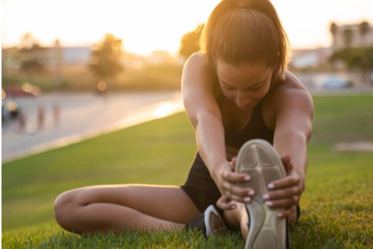 mulher se alongando antes de praticar exercício físico