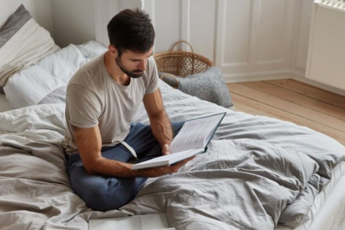 homem lendo livro na cama