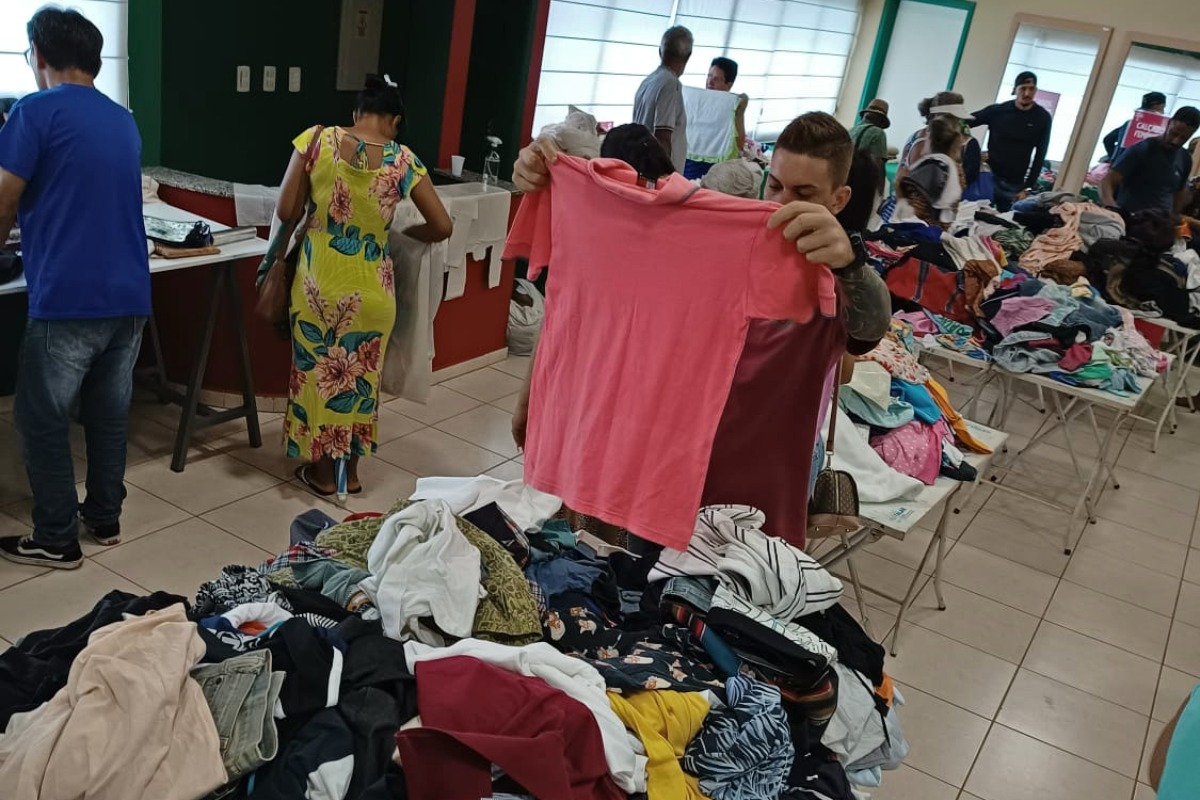 Cliente examina camiseta em bazar da AACC