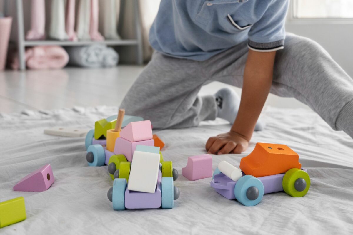 Criança brincando com brinquedos coloridos no chão, foto ilustrativa para hipertensão infantil