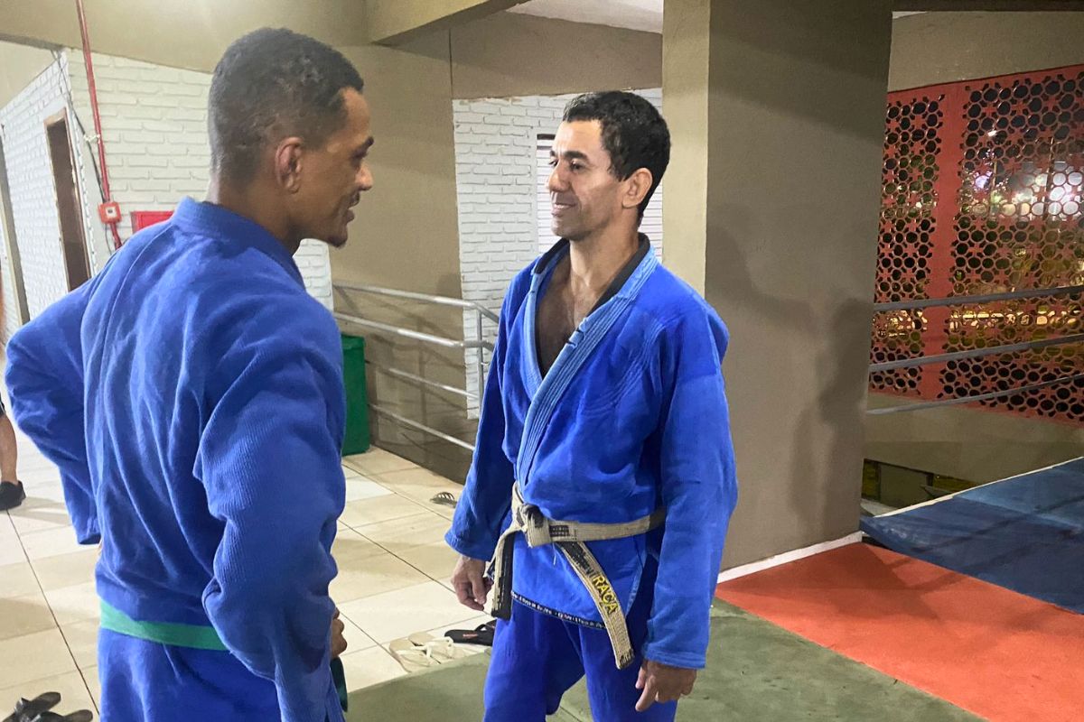 Dois atletas de judô se preparando para lutar. Ambos estão de kimono azul.