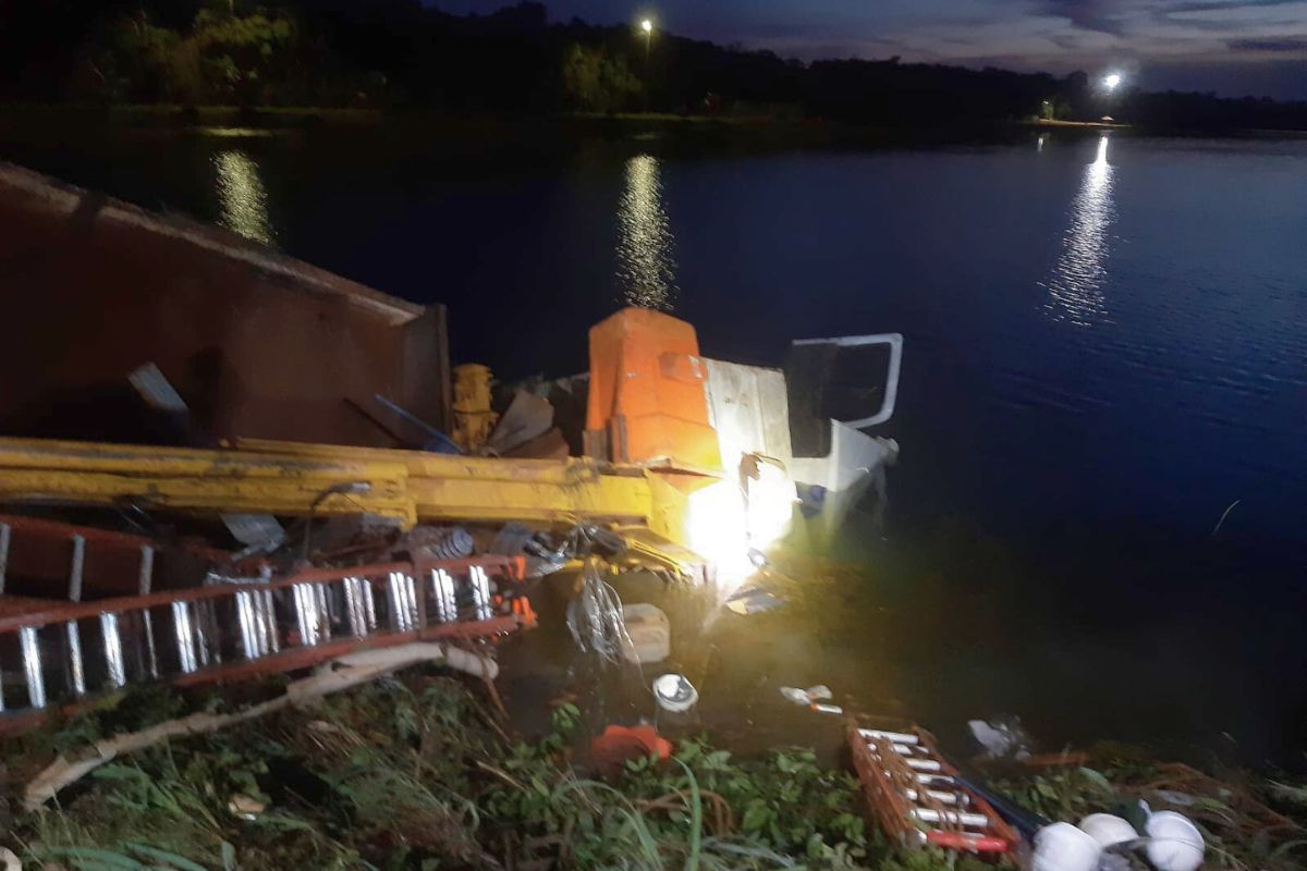 Imagem mostra local do acidente que deixou um trabalhador morto e quatro feridos, caminhão aparece tombado com parte da cabine submersa no lago 